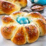 Braided Italian Easter Bread decorated with colorful eggs and rainbow sprinkles on a rustic wooden table