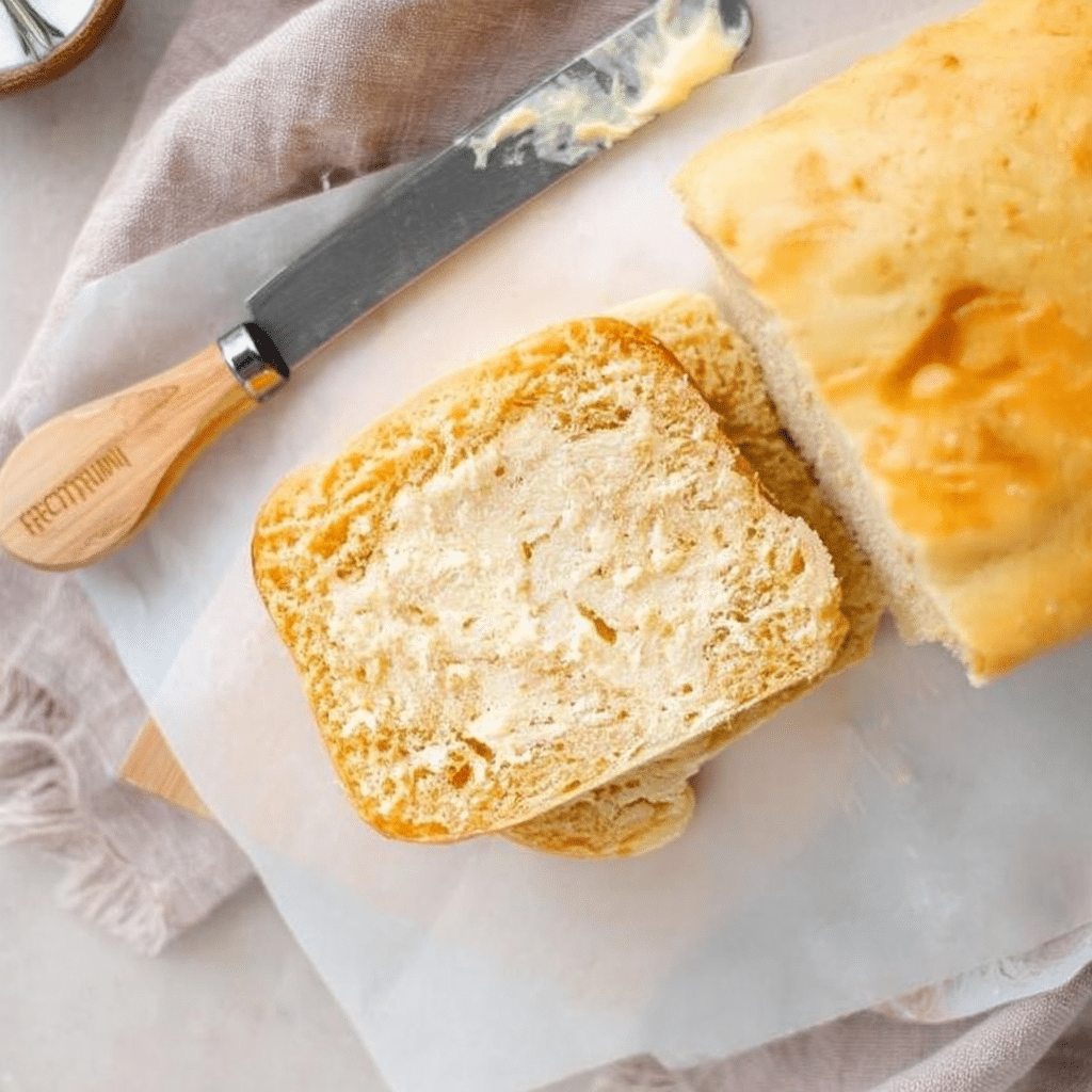Keto friendly bread loaf sliced on a wooden board with fresh rosemary