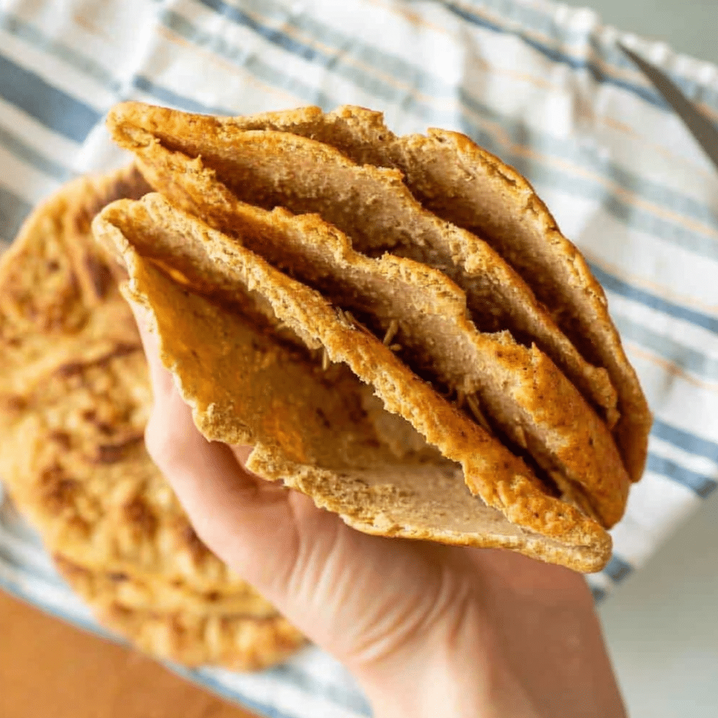 Low carb keto pita bread stacked on a wooden board with herbs